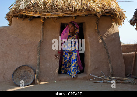 Indische Frau trägt einen Sari heraustreten aus dem Eingang der Hütte, Stovewood liegt vor der Hütte, Thar-Wüste Stockfoto