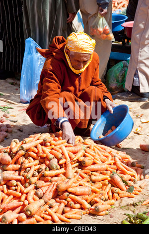 Markt-Händler tragen traditionelle Djellaba mit Karotten auf einem Markt oder Souk, Ounila Tal, Atlasgebirge, Marokko Stockfoto