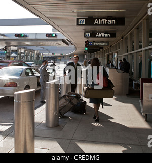 Die Leute nehmen ihre Sachen vor dem Betreten der Flughafen La Guardia in New York City. Stockfoto