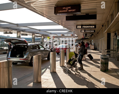 Die Leute nehmen ihre Sachen vor dem Betreten der Flughafen La Guardia in New York City. Stockfoto