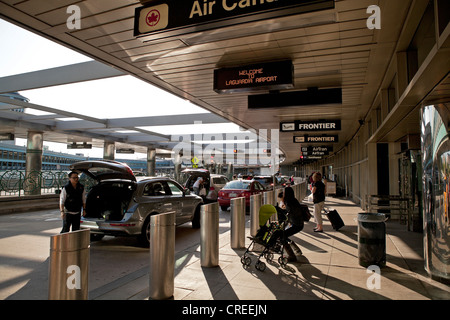 Die Leute nehmen ihre Sachen vor dem Betreten der Flughafen La Guardia in New York City. Stockfoto