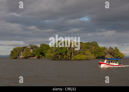 Ausflugsschiff vor der kleinen Insel mit tropischer Vegetation im Nicaragua-See, Isletas, Lago de Nicaragua, Nicaragua Stockfoto