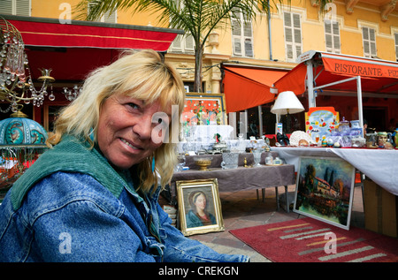 Frau Inhaber Verkauf von Gemälden und Kunstwerken in der antiquitätenmarkt Abschaltdruck am Vieille Ville Altstadt, Nizza, Côte d'Azur, Frankreich Stockfoto