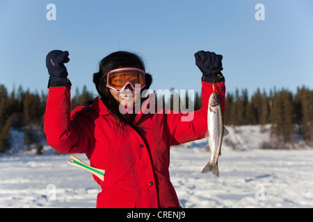 Junge Frau präsentieren ihren Fang, Regenbogenforelle (Oncorhynchus Mykiss), Eisfischen auf einem zugefrorenen See, Yukon Territorium, Kanada Stockfoto