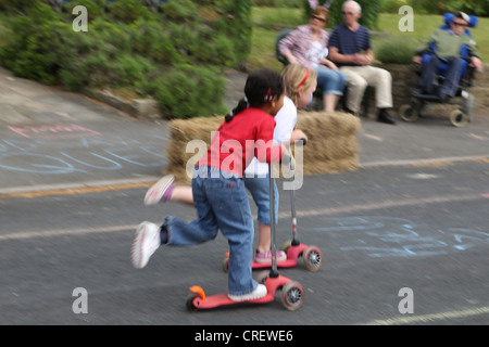 Menschen feiern die Königin Diamond Jubilee Kinder, die In einem Roller-Rennen in A Street Party Surrey England teilnehmen Stockfoto