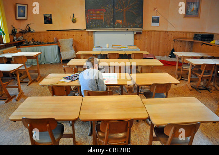 acht Jahre alten Schüler sitzen einsam im Klassenzimmer Stockfoto