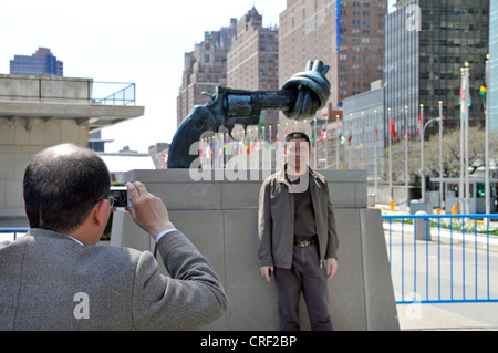 Touristen die Souvenir-Fotos vor der verknoteten Gewehr, Gewaltlosigkeit Skulptur aus Reuterswaerd vor UN-Hauptquartier, USA, USA, New York City, Manhattan Stockfoto