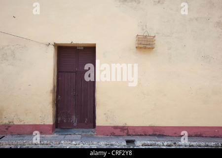 Tür des Gebäudes mit Vogelkäfig an Wand in Trinidad, Kuba. Stockfoto