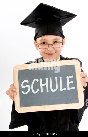 symbolisch für die Schule. Kleiner Junge als Diplom-Inhaber mit einer Tafel Stockfoto