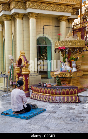 Myanmar, Burma, Yangon. Sule-Pagode. Frau beten vor Buddha-Statue. Stockfoto