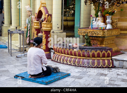 Myanmar, Burma, Yangon. Sule-Pagode. Frau beten vor Buddha-Statue. Stockfoto