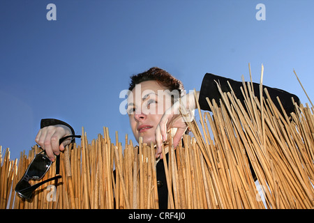 Frau mit Sonnenbrille in der Hand mit Blick auf eine Strohmatte Stockfoto
