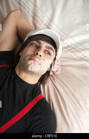 Nachdenklicher junger Mann auf Bett liegend Stockfoto