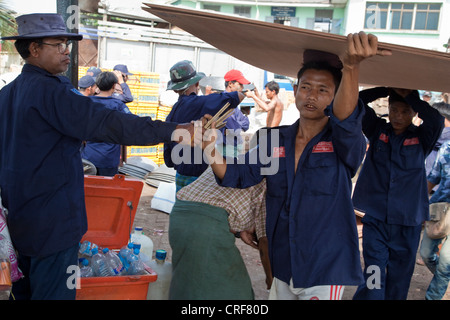 Myanmar, Burma, Yangon. Tally Mann austeilen Tally Sticks, Stauer tragen Sperrholzplatten Boot in Yangon River. Stockfoto