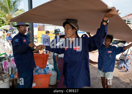 Myanmar, Burma, Yangon. Tally Mann austeilen Tally Sticks, Stauer tragen Sperrholzplatten Boot in Yangon River. Stockfoto