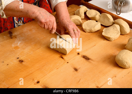 Ältere Frau schneiden Teig an Bord Stockfoto