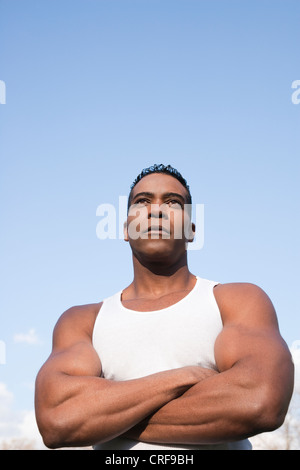 Zuversichtlich, US-amerikanischer Bodybuilder mit verschränkten gegen blauen Himmel Stockfoto