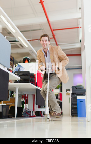 Geschäftsmann Reiten Scooter im Büro Stockfoto