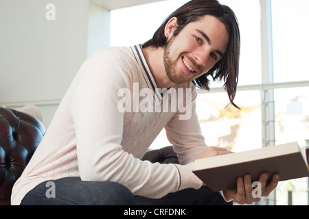 Porträt eines fröhlichen jungen Mannes, ein Buch zu lesen Stockfoto