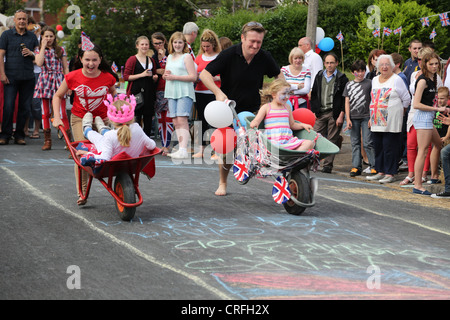 Menschen feiern die Königin Diamond Jubilee Teilnahme an einem Schubkarren-Rennen auf A Street Party Surrey England Stockfoto