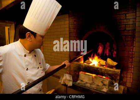 Ente-Chef hebt Enten innerhalb und außerhalb der Öfen. Quanjude Roast Duck Restaurant in Wangfujing, Beijing Stockfoto