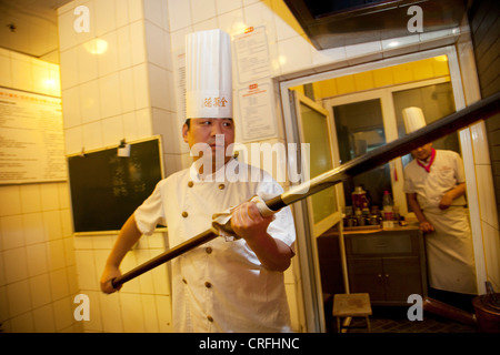 Ente-Chef hebt Enten innerhalb und außerhalb der Öfen. Quanjude Roast Duck Restaurant in Wangfujing, Beijing Stockfoto