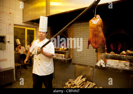 Ente-Chef hebt Enten innerhalb und außerhalb der Öfen. Quanjude Roast Duck Restaurant in Wangfujing, Beijing Stockfoto