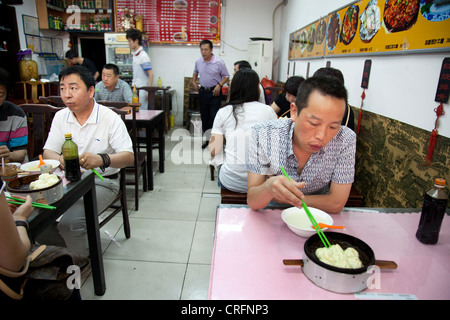 Mann chinesische Knödel zum Frühstück in einem kleinen Restaurant im Xuanwu District, einem Gebiet südlich von Tiananmen, Beijing. Stockfoto