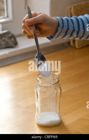 Kinder experimentieren und Kristalle wachsen. Schritt 1: Salz in Glas füllen Stockfoto