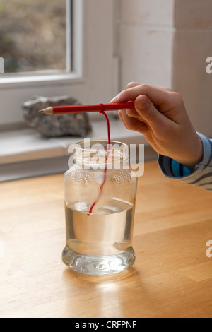 Kinder experimentieren und Kristalle wachsen. Schritt 4: Garn hängen in Salzlösung Stockfoto