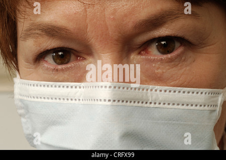 Gesichtsbesamung Nahaufnahme von einer reifen Frau mit weit aufgerissenen Augen tragen einen Mundschutz. Stockfoto