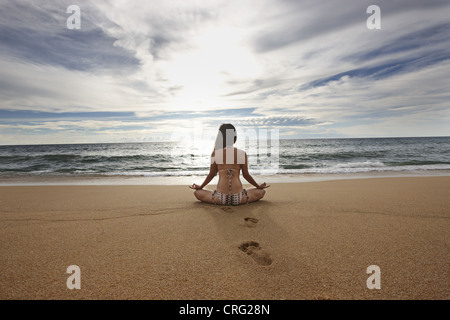 Frau am Sandstrand zu meditieren Stockfoto