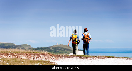 Zwei männliche Wanderer Fuß entlang der Felskante in Richtung Belle Tout Leuchtturm auf der South Downs in East Sussex an einem warmen Sommertag Stockfoto