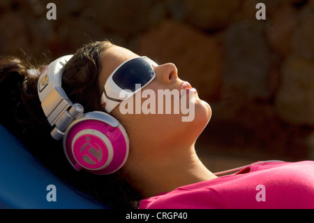 junge Frau mit Sonnenbrille und Kopfhörer Stockfoto