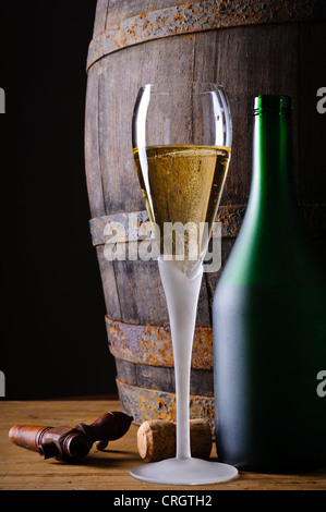 Stillleben mit Glas und Flasche Champagner oder prosecco im Keller mit Holzfass Stockfoto