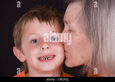 Großmutter setzt auf Enkel Wange ein schmusig Stockfoto