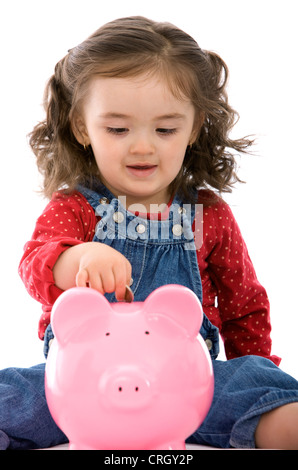 kleines Mädchen, eine Münze auf ihr Sparschwein Stockfoto