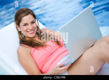 Frau, die in einem Schwimmbad mit Notebook bequem arbeiten Stockfoto