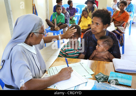 Katholischen Schwester und ausgebildete Krankenschwester untersucht junge Patienten in einem Krankenhaus in Tapini Dorf, Papua-Neu-Guinea Stockfoto