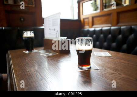 Pint of stout on the table of a booth in the inior of the Crown Liquor Saloon Bar Pub in belfast, Northern ireland UK Stockfoto