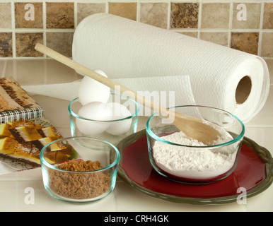 Backen, Werkzeuge und Zutaten mit braunem Zucker Eiern Mehl im Glas Schalen Satz bis auf Küchentisch gegen gefliesten Aufkantung Stockfoto