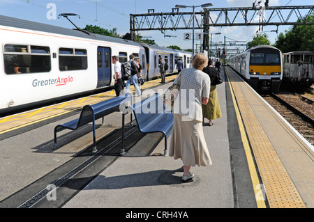 Frauen & andere Passagiere warten am Bahnsteig, an Bord zwei größere Anglia Pendlerzügen nach London Liverpool Street England Großbritannien Stockfoto