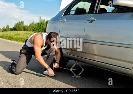 Mechaniker, die ein Auto mit Jack-Schraube anheben Stockfoto