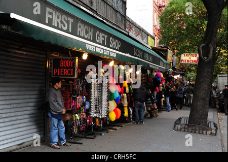 Orientalische Mann unter roten Neon Piercings Zeichen neben ersten Rich-Geschenk-Shop, St. Mark's Place, East Village, New York Stockfoto