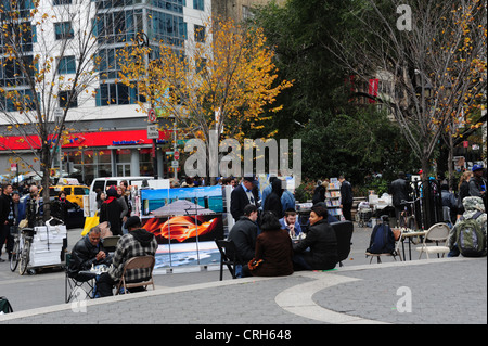 Herbst Baum Blick auf Studienplatz, Kunst Stall Menschen gehen, sitzen, Männer spielen Schach, Union Square West, NewYork Stockfoto