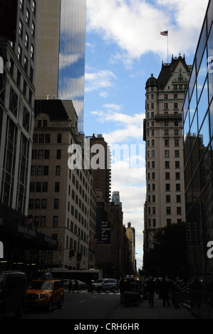 Blauer Himmel weiße Wolken Schatten Porträt East 58th Street in Richtung 5th Avenue, American Flag Plaza Hotel Solow Building in New York Stockfoto