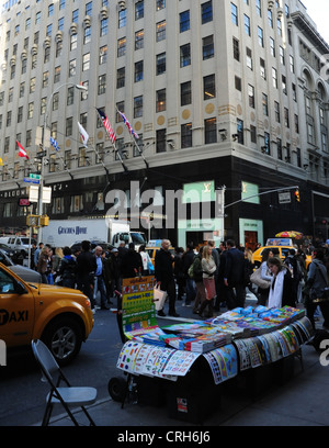 Bloomingdale's Store, Bürgersteig Stall zu verkaufen pädagogische Plakate, Menschen überqueren East 59th Street in Lexington Avenue in New York Stockfoto