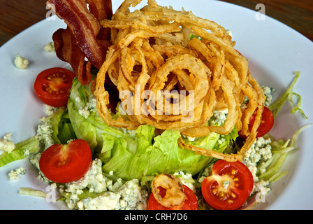 Speck zerbröckelte Blauschimmelkäse Cherry Tomaten knusprig tief gebratene Zwiebel Ringe Salat Keil Salat Vorspeise Stockfoto