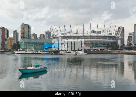 Eine Yacht sitzt ruhig im Wasser auf False Creek Vancouver an einem bewölkten Tag direkt vor das BC Place Stadium. Stockfoto