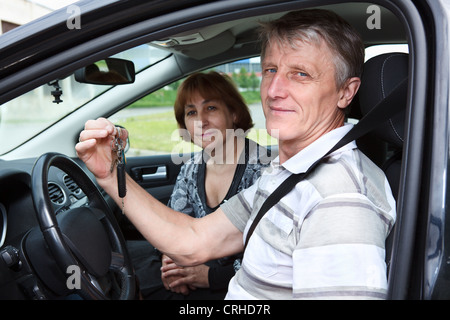 Kaukasische Senior Mann und Frau in Landfahrzeug mit Zündschlüssel lächelnd. Seitenansicht Stockfoto